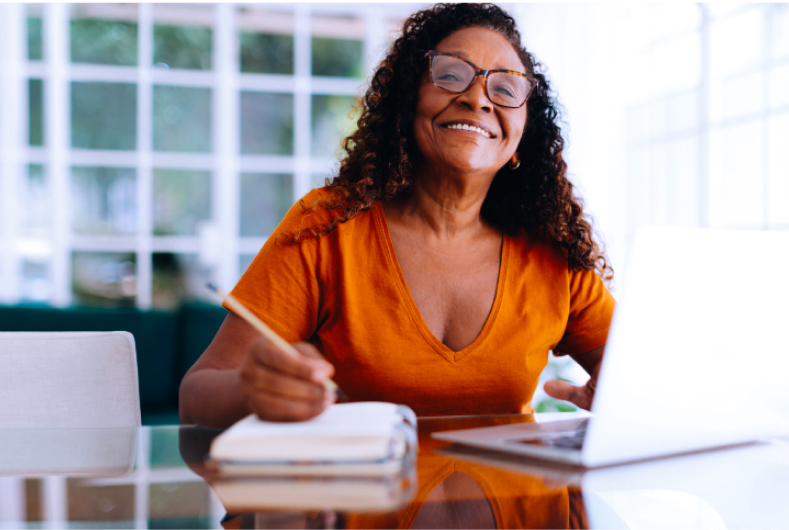 Mulher sorrindo com blusa na cor laranja.